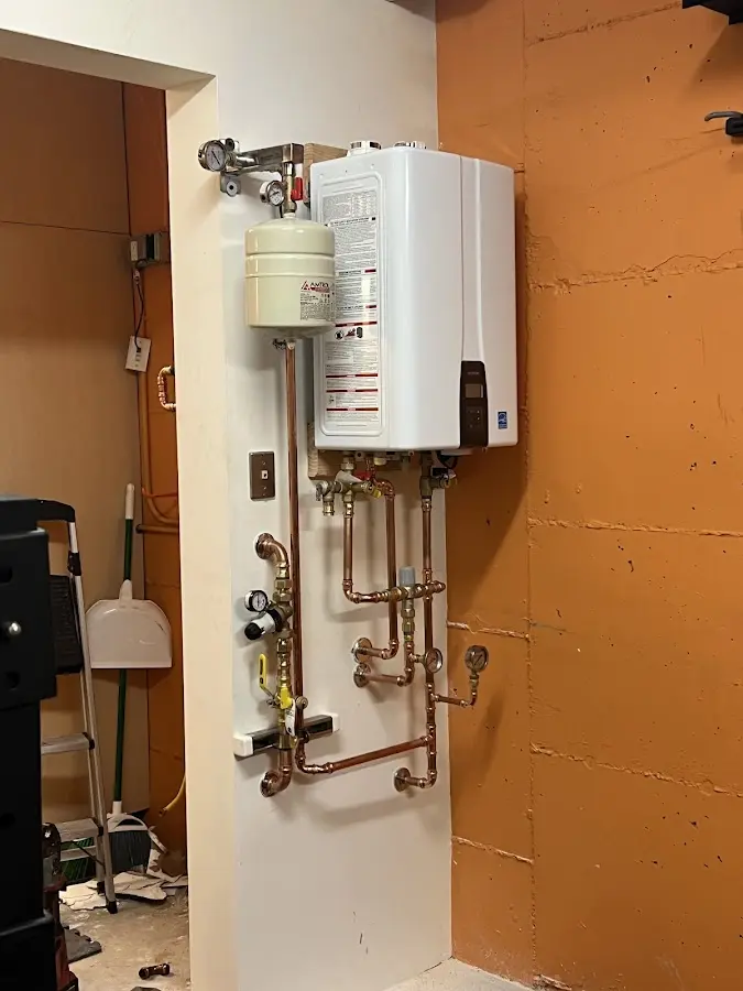 Plumbing technician inspecting water heater connections in North Hempstead